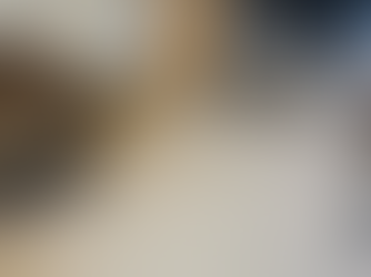 Living room with brown recliner, wooden table, large TV on rustic wood wall. Fish decor, beige carpet, and door in background. Cozy vibe.