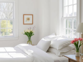 a high-quality shot of a sun-drenched guest bedroom featuring crisp white linens and a vase of fresh tulips on the nightstand.