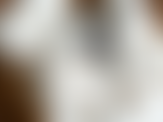 A basket filled with neatly folded, light-colored linen blankets and a sprig of dried lavender.