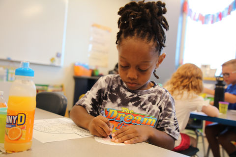 A young male student working on his coloring page with concentration and calmness