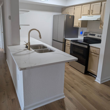 Transitional-style kitchen featuring marble-look countertops, white cabinetry, and a brushed gold faucet. A subtle mix of modern and classic elements for a fresh update.