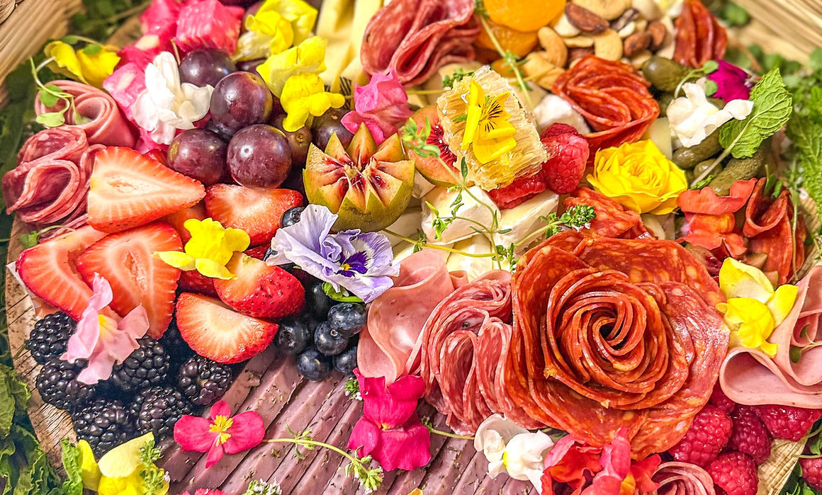 Vibrant charcuterie board with artisan cheese and charcuterie with edible flowers and fresh fruit