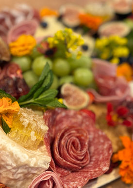 A vibrant charcuterie board with cheese, grapes, apple slices, and various meats.