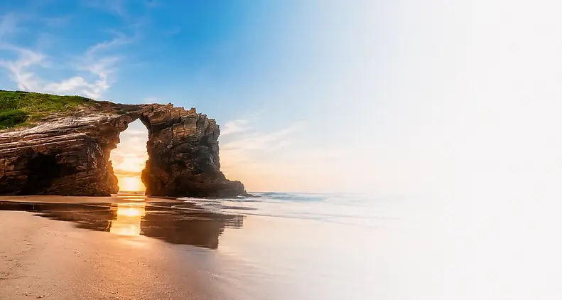 Playa de Las Catedrales en Ribadeo vista al amanecer, con los impresionantes arcos de roca esculpidos por el mar y acceso desde Tapia de Casariego.