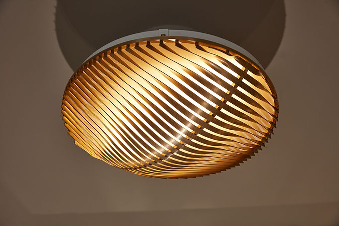 Plafonnier en forme de disque lumineux filtré par une trame en laiton