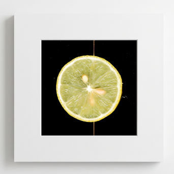 A scanography artwork of a lemon slice centered on a black background, seeds and textures glowing under light, framed with a white border.