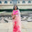 Thumbnail: Model wearing a pink silk saree hand painted with florescent pink bougainvillea's posing in front of monument in Hampi