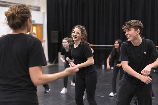 Young performers working with a West End professional during a musical theatre workshop