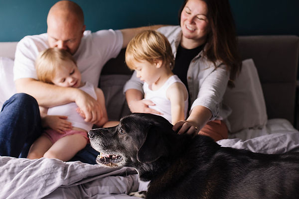 amanda hughes and family with husnad twins and dog sitting on bed