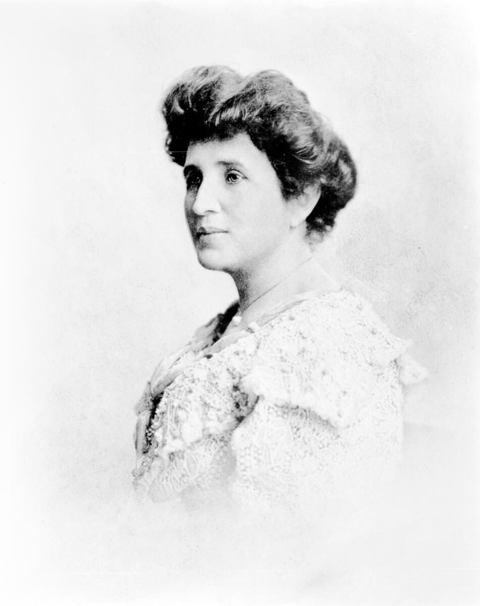 A woman in an elegant lace dress, posed side profile. The black and white image has a soft, serene background conveying a calm mood.