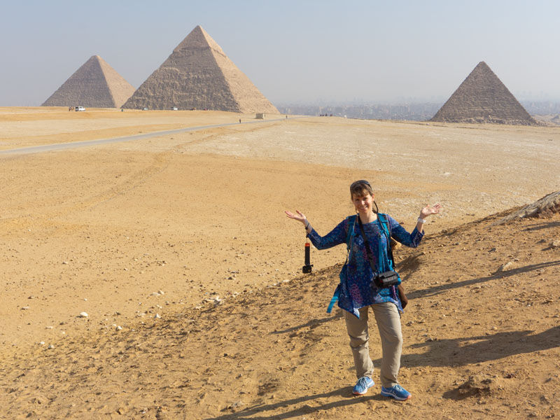 a woman standing in front of the pyramids of Giza