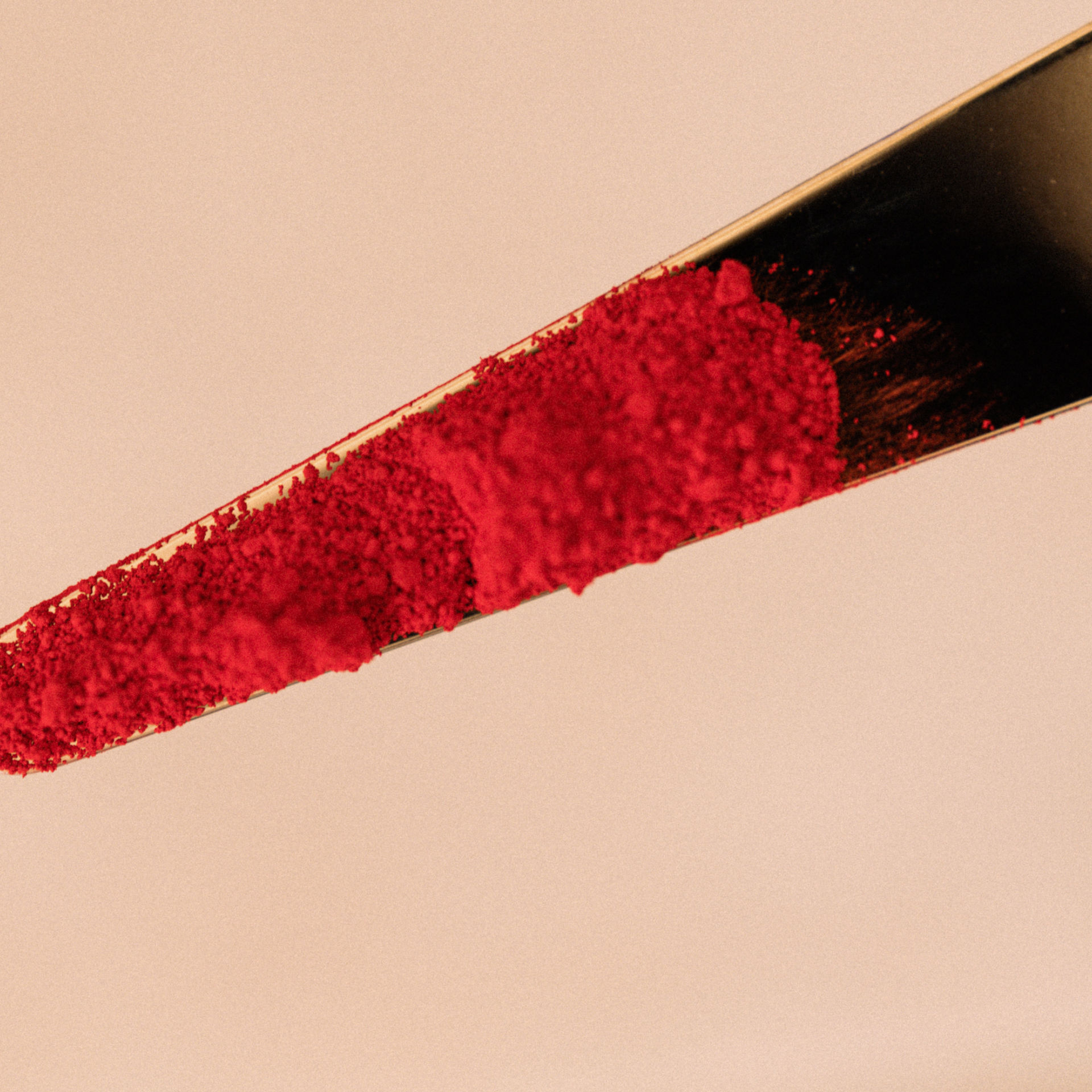 Bright red  pigment powder on a metal spatula