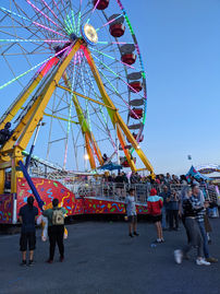 A rainbow colored Ferris wheel against a twilight sky.