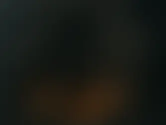 A monumental stone entrance carved into a mountain cliff, flanked by two towering dwarf statues holding great hammers. Warm firelight glows from braziers beside the massive wooden doors, casting shadows across the ancient dwarven architecture.