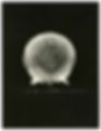 A black-and-white image of an atomic bomb explosion creating a circular, nebula-like pattern against a dark background with a dotted texture.