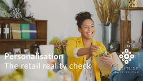 Smiling woman in yellow jacket handing over a purchase. Text: Personalisation The Retail Reality Check