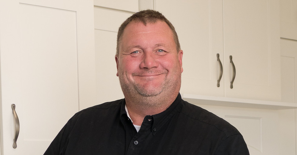 man standing in cabinet showroom wearing black polo