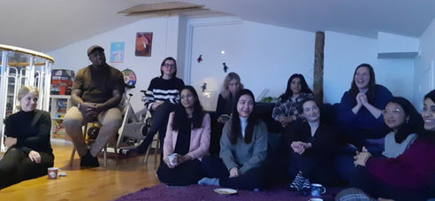 Team members sit on the floor of a living room.