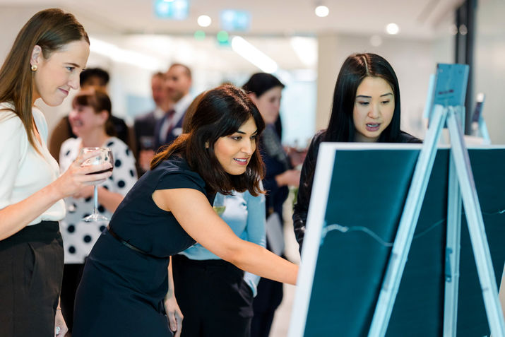 Employees looking at Fanny Berthiaume's artwork at the Fiera Capital Toronto Art Show.