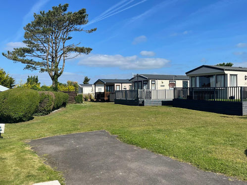 Open grass area with three light caravans in the background.