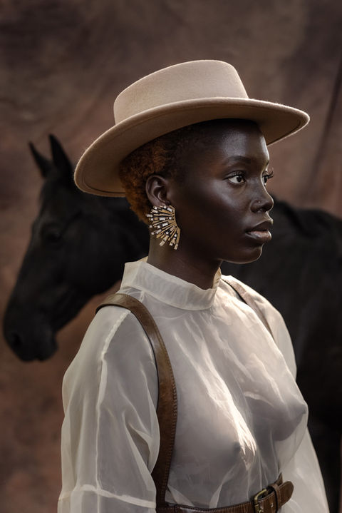 Shooting in Düsseldorf 2024 with Horsey nature vibes. Brown background and black horse. Dark skin. Earring. Seethrogh.