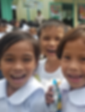 Three young schoolchildren in the Philippines smiling happily at the camera