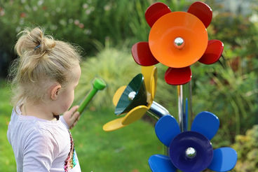 A little girl stands while playing the harmony flowers. 