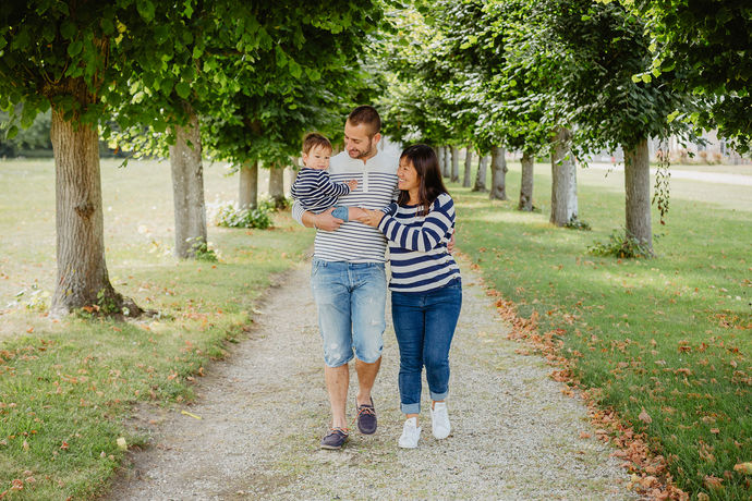 parents en marinière portant leur jeune fils dans les bras. ils sont en pleine nature au milieu des arbres verts