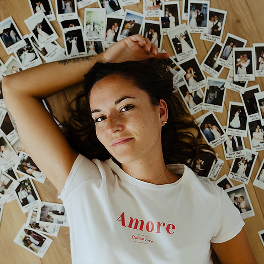 Portrait de Mélanie Vaury allongée sur le sol et entourées de photos polaroid