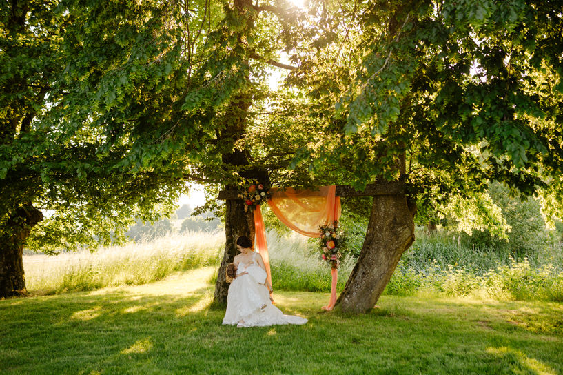 Mariée allaitant sa fille sous les arbres.
