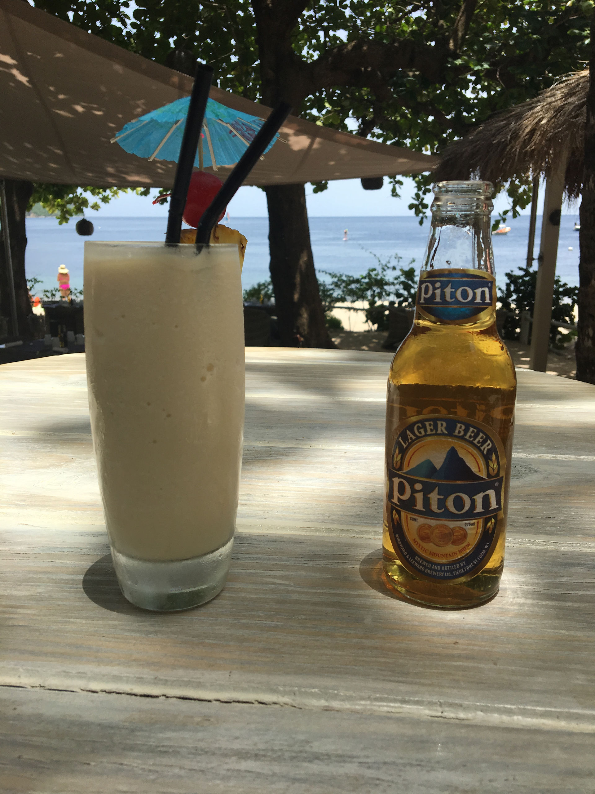 A Piña Colada & Piton Beer at the beach bar. Pitons Bay in the background.