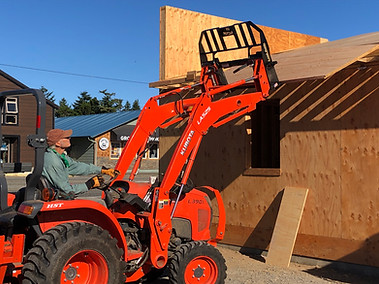 Photo of plywood being lifted onto the roof with heavy equipment.