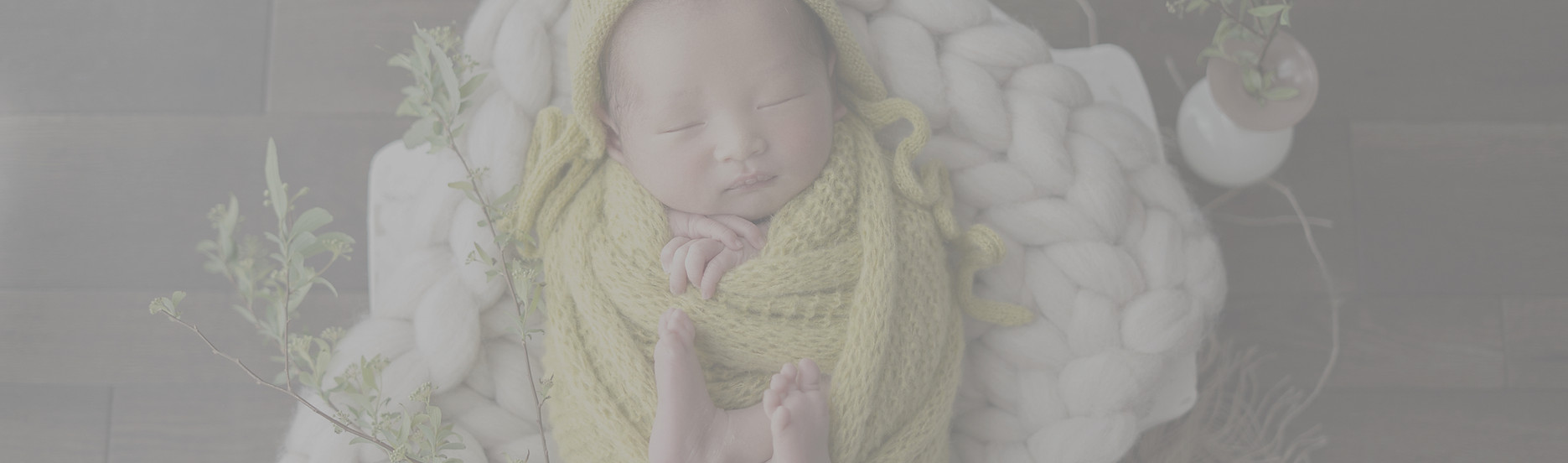 羊毛の上におくるみで包まれる新生児