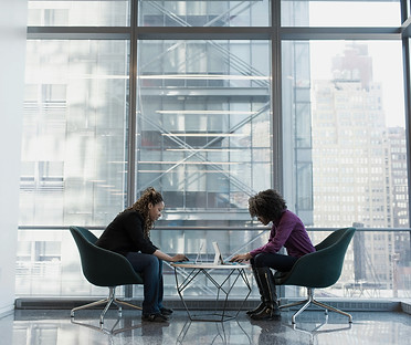 two women sits of padded chairs while us