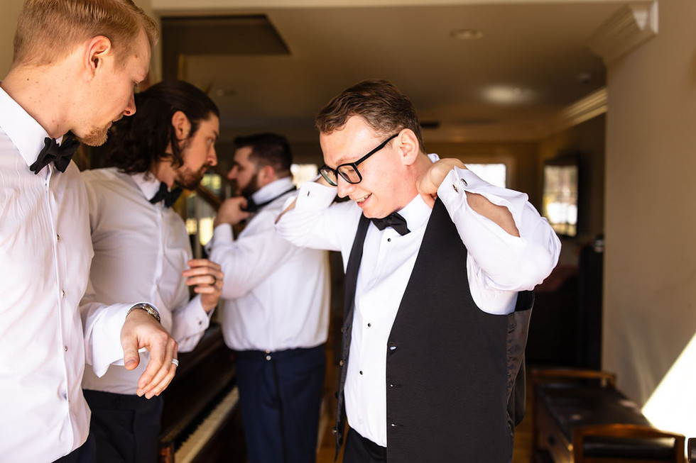 a groom putting on his suit vest in Lititz Pennsylvania