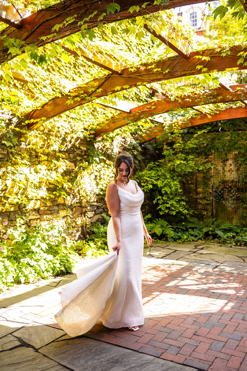 bride in white beaded wedding gown swirling the train in a garden terrace at Excelsior in Lancaster Pennsylvania