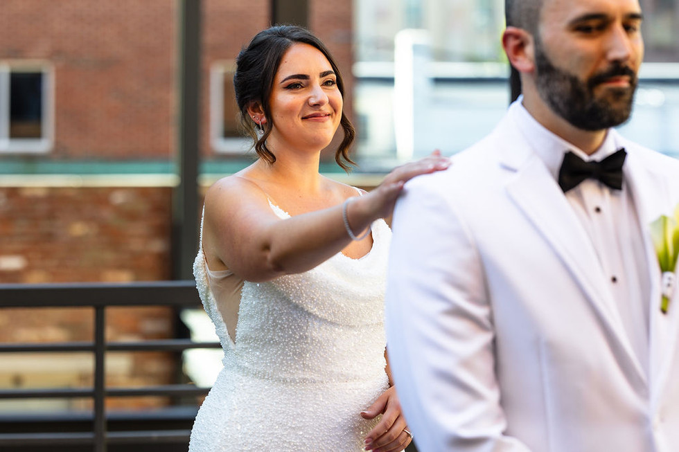 a bride in a beaded wedding gown tapping the shoulder of the groom in a white suit jacket at Excelsior in Lancaster Pennsylvania
