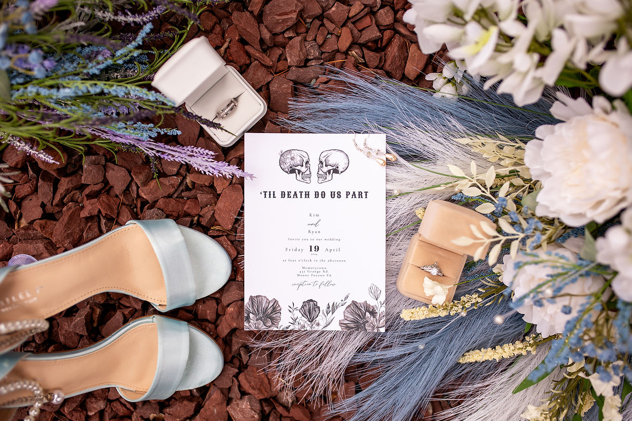 flat lay of blue wedding shoes rings bouquet and invitation 