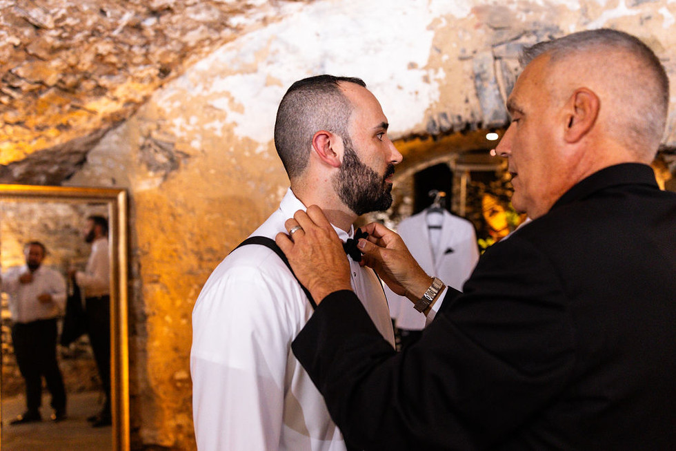 father putting a black bow tie on the groom in a cellar at Excelsior in Lancaster, Pennsylvania