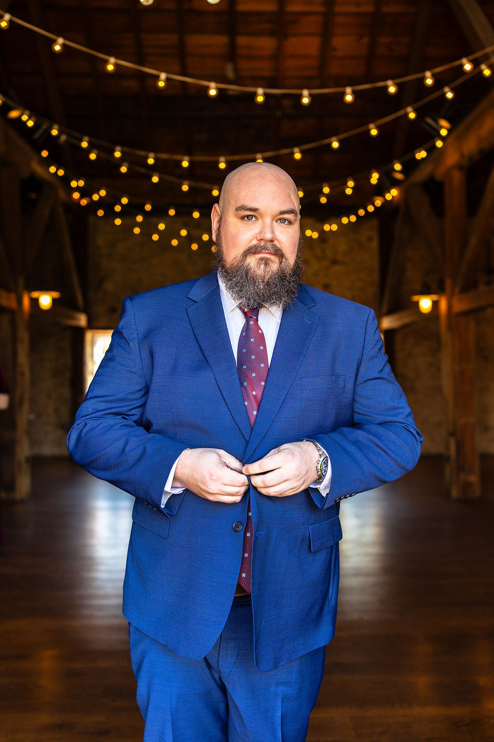 a groom buttoning his blue suit at Tyler Arboretum in Media, Pennsylvania