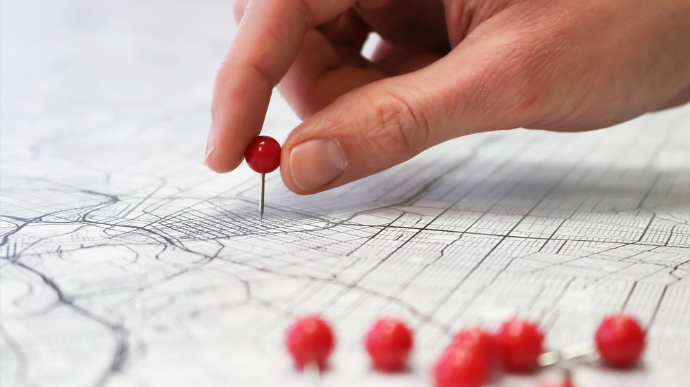 photo of a person's hand placing a pin on a map
