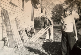 Man putting on old fashioned storm windows while young girl watches eating an ice cream cone