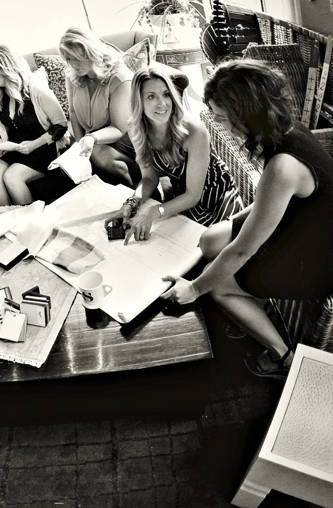 Interior designers around a table collaborating on floor plans and fabrics.