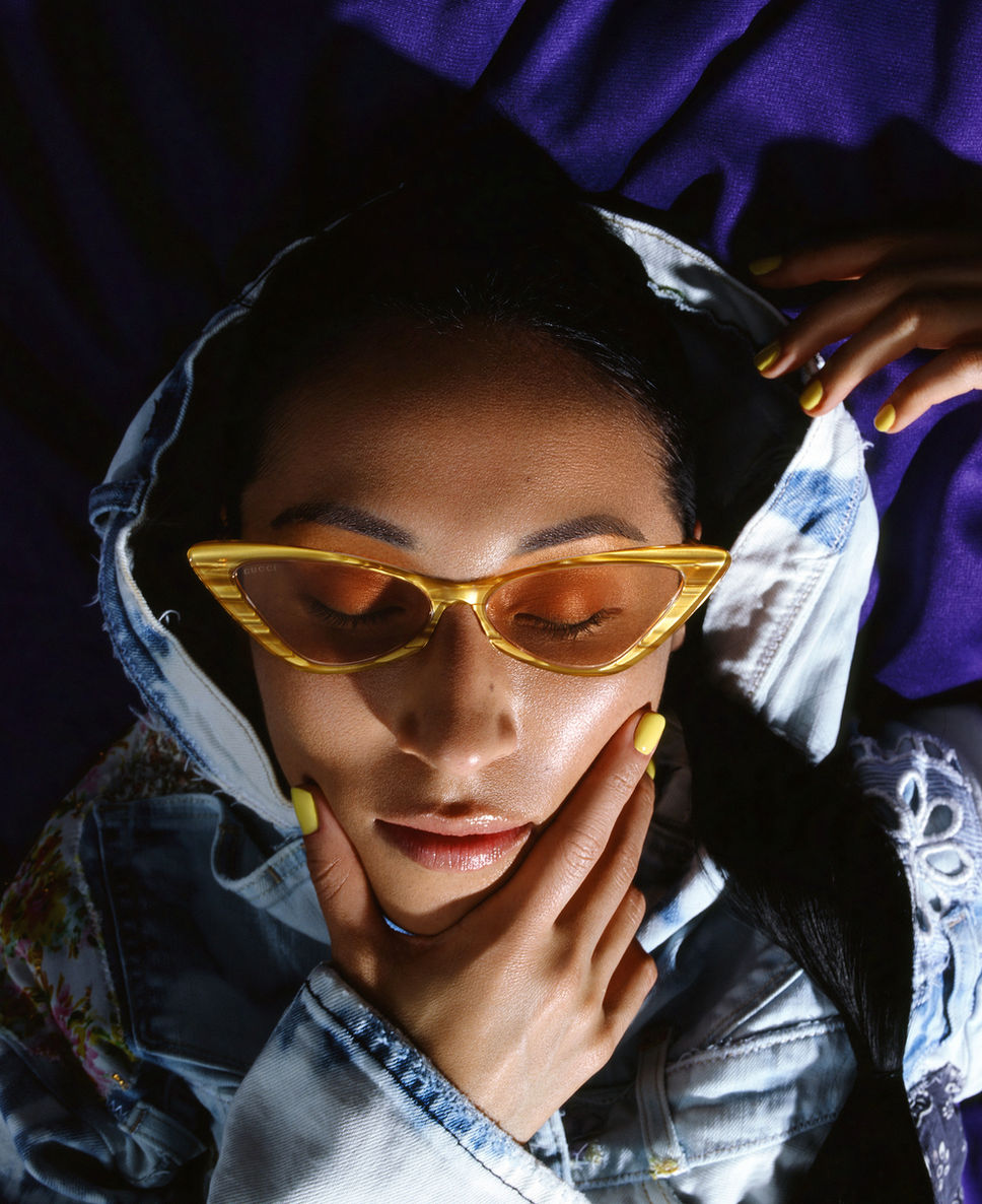 Retro Glamour Reimagined: In a vivid celebration of style and color, this film photograph by Jesse Jacques Photo captures a model wearing a colorful jean jacket and mini skirt, complemented by vintage yellow Gucci cat-eye glasses and matching nail polish. Her long black hair, elegantly braided, adds to the allure. The use of Kodak Ektachrome 100 slide film imparts a timeless quality, reflecting a unique fusion of past and present. Explore more at jessejacquesphoto.com