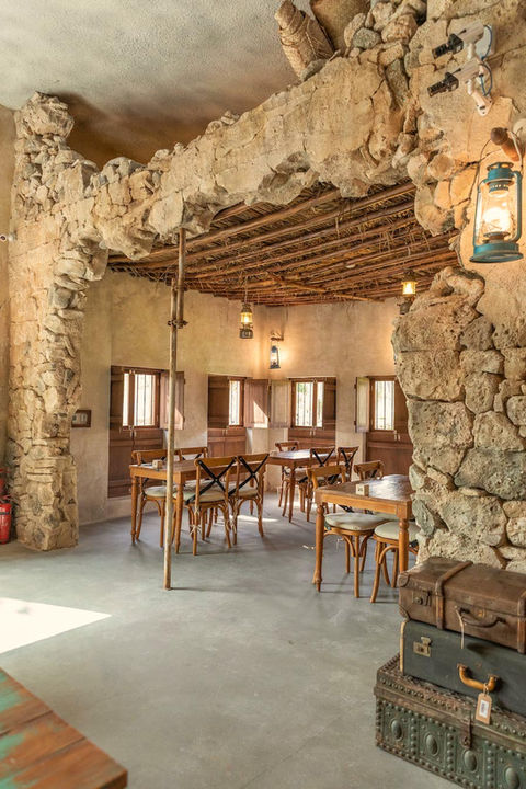 stone archway and wooden tables, featuring a rustic design with hanging lanterns and natural lighting