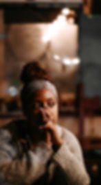 Worried black woman wearing a knot sweater and headband with her hands over her mouth.