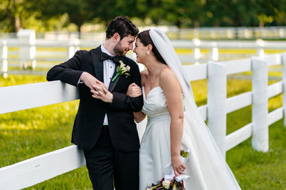 Bride and groom giggling by fence