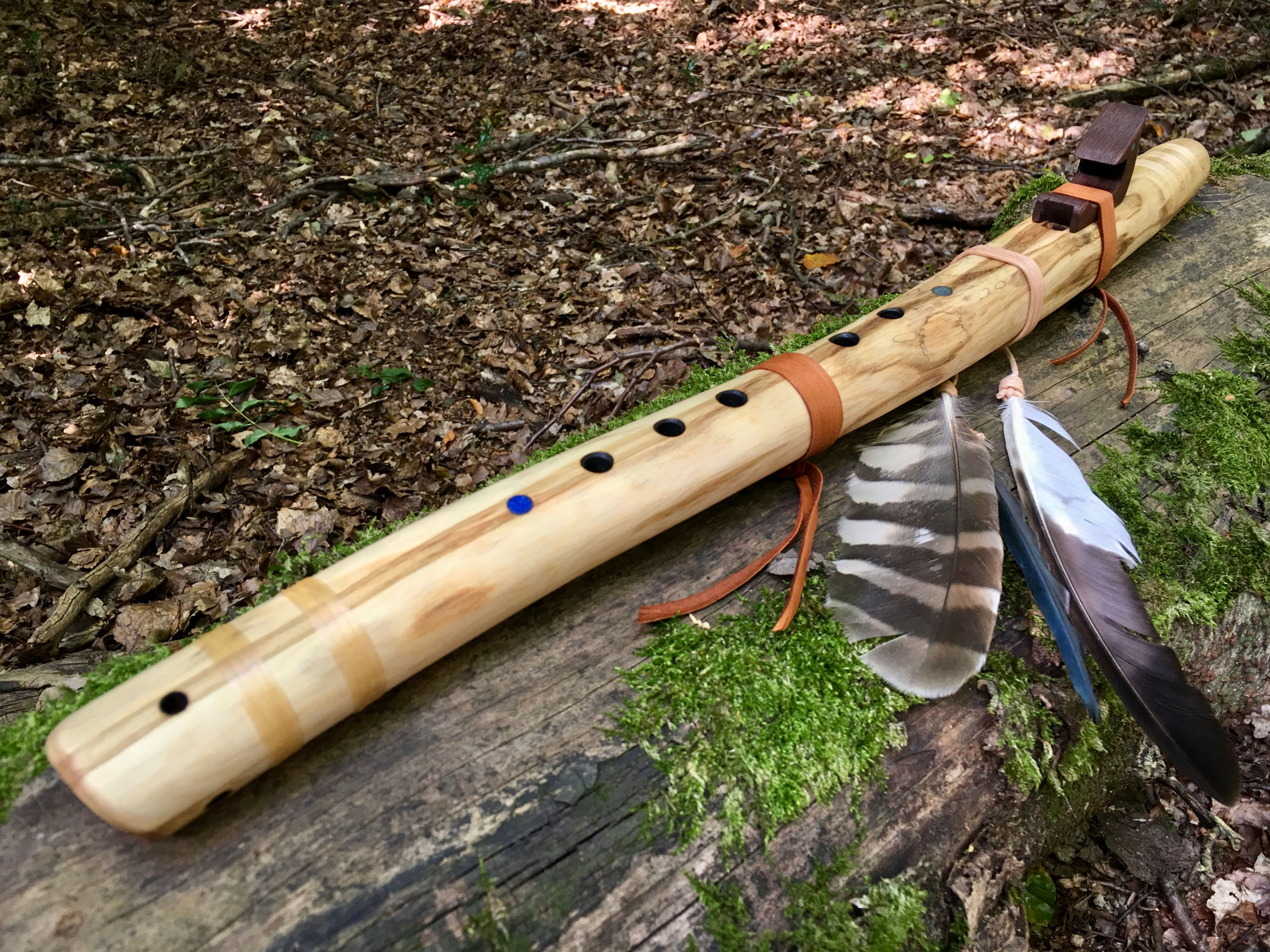 Handcrafted Native American style flute made with American Angelica and walnut totem on log with autumn leaves.