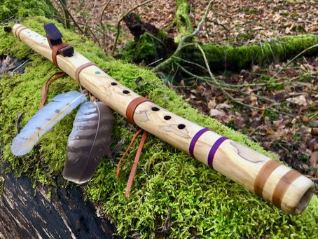 Native American style flute made of Ash with Owl feathers in mossy forest
