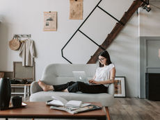 Virtual Assistant in modern living room comfortably working on laptop, embodying a relaxed and productive atmosphere.